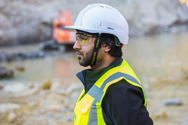 Construction worker in safety gear and hard hat at a rocky site.
